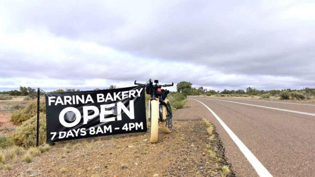 kate's bike propped up against a sign saying teh bakery is open