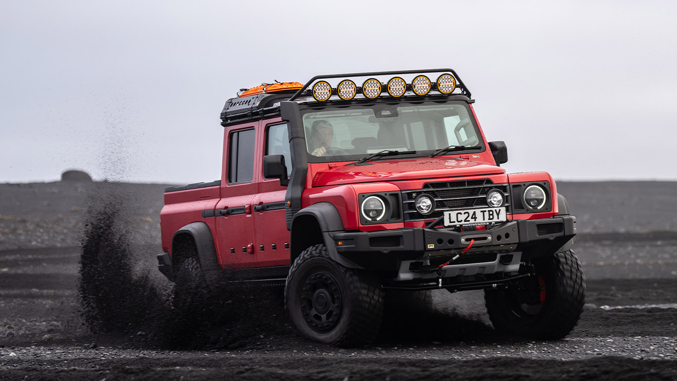 red ineos grenadier quartermaster with portal axles kicking up the dust in iceland