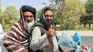 two men on their motorcycle in Afghanistan showing a thumbs-up