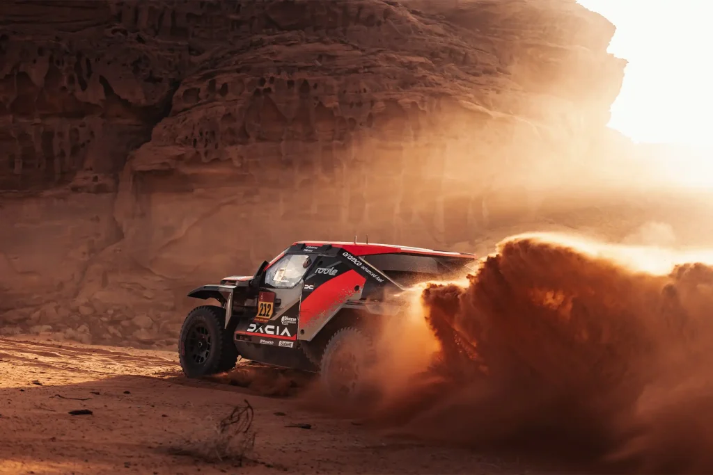 dacia sandrider charging into the sunset and kicking up a lot of sand