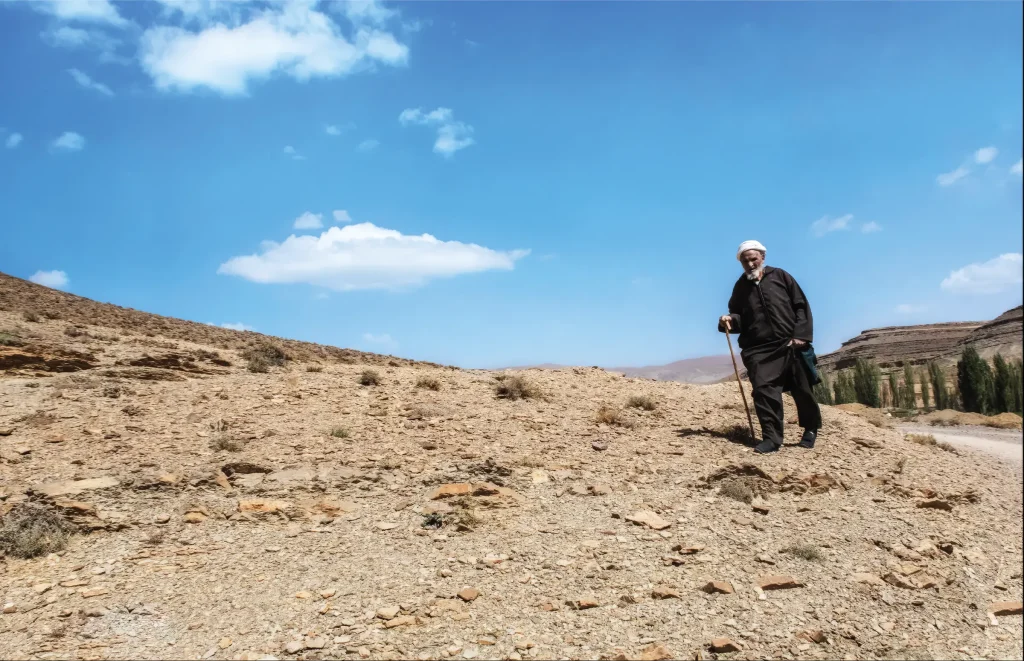 Older man standing in the arid landscape of Morocco’s Atlas Mountains.