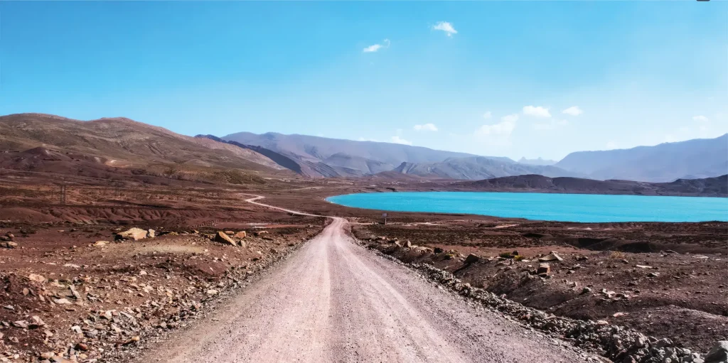 Turquoise mountain lake beside an unpaved road in Morocco’s High Atlas.