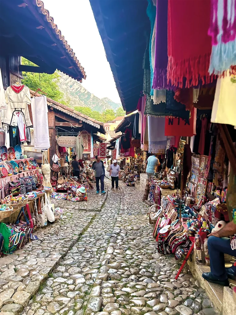 Cobblestone market street lined with colourful textiles, crafts and souvenir stalls in Albania.