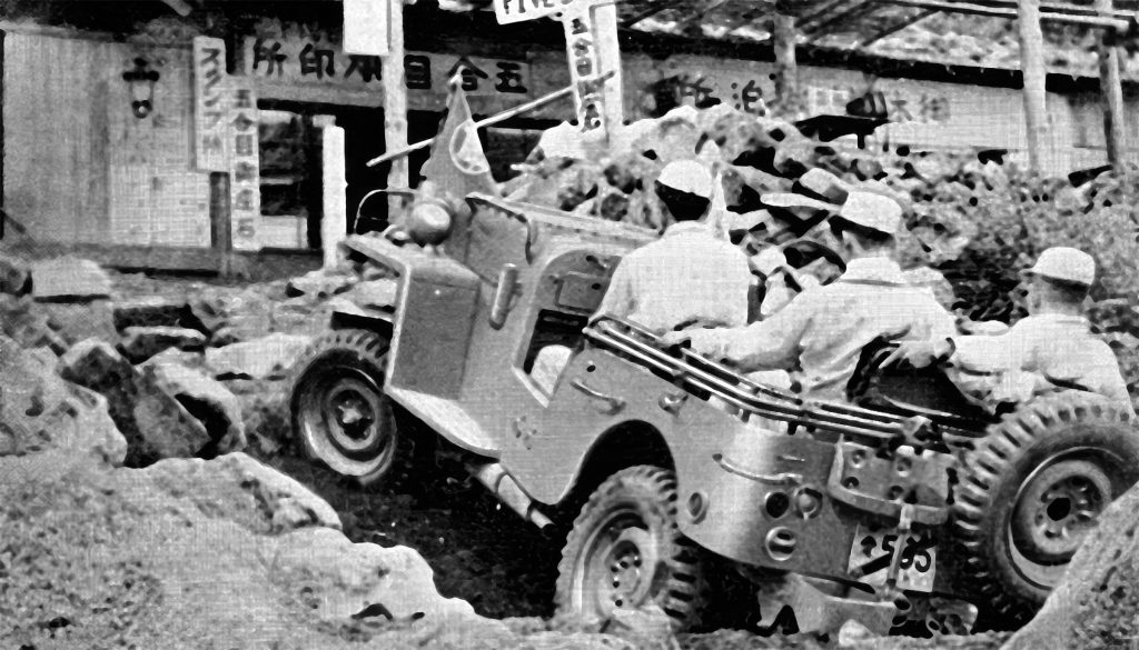 Early Toyota Land Cruiser climbing over rough terrain during an off-road demonstration in Japan.