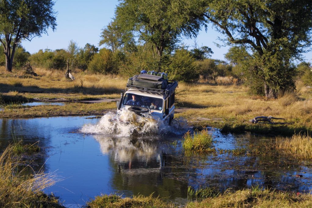 Adrian Stratta and Catherine crossing a water obstacle in a Land Rover Defender during their overland journey through Africa.