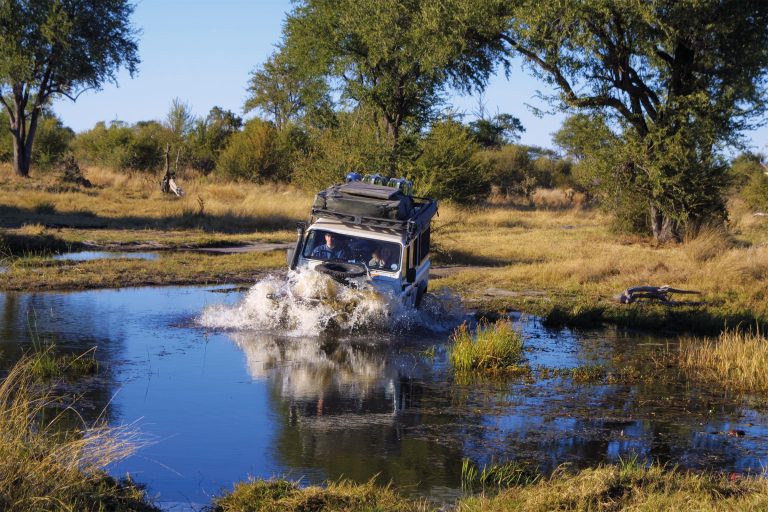 Adrian Stratta and Catherine crossing a water obstacle in a Land Rover Defender during their overland journey through Africa.