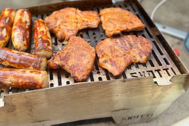 Sausages and chicken cooking on a well-used SKOTTI Gas Grill.